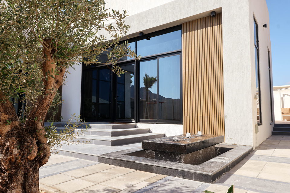 A mature olive tree and stone water feature framing a villa entrance, project A35